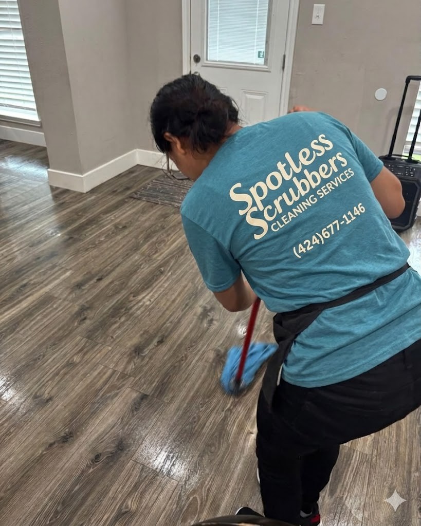 Spotless Scrubbers cleaner mopping hardwood floors in branded shirt