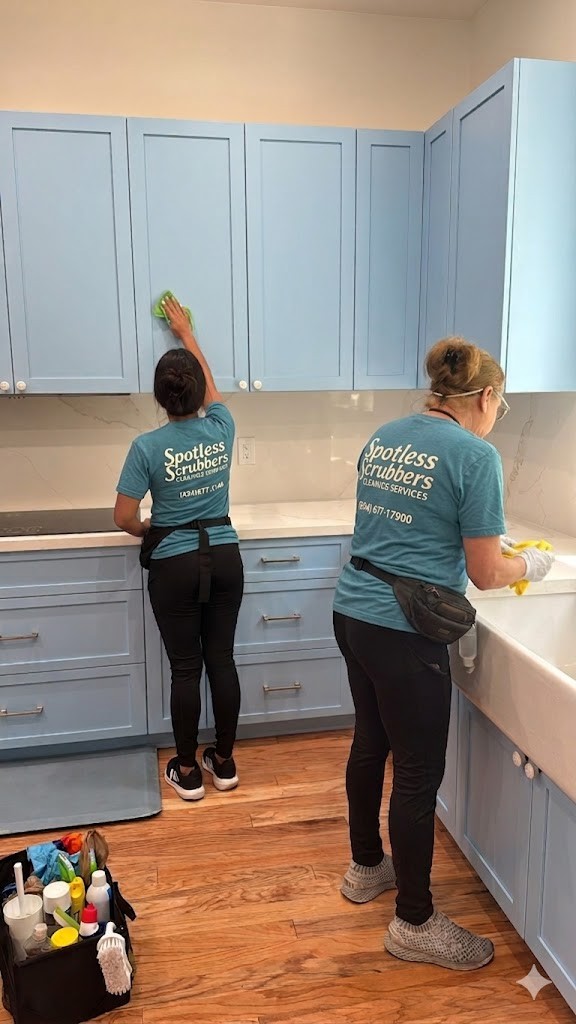 Two Spotless Scrubbers cleaners wiping down kitchen cabinets and sink