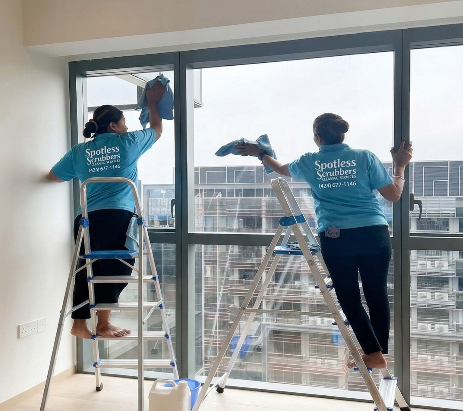 Spotless Scrubbers team cleaning windows on ladders in branded shirts